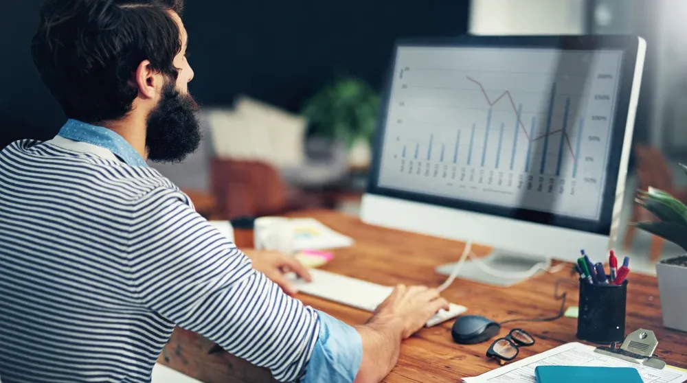 Digital marketing specialist analyzing Google Ads campaign performance on large monitor