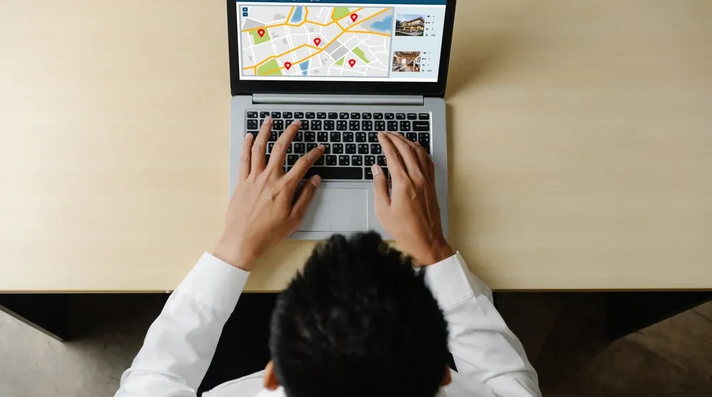 Franchise business owner reviewing multi-location Google Maps performance dashboard on laptop in modern office