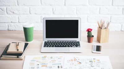 Clean desk with laptop, cactus and notebooks representing how to write Google Ads copy
